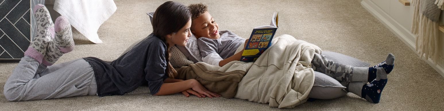 Two children reading on a carpeted floor