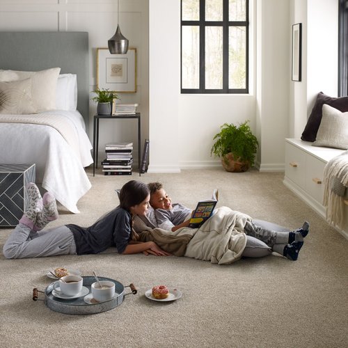 Two children reading on a carpeted bedroom floor
